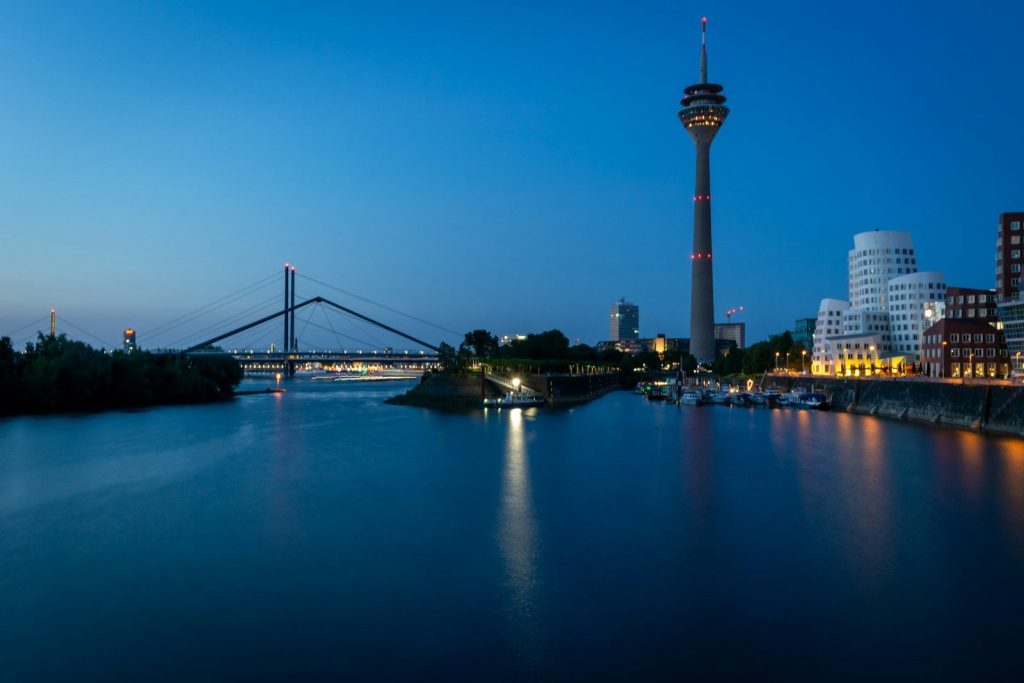 Dusseldorf skyline at night with bridge and tower.