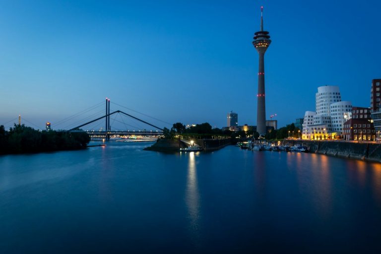 Dusseldorf skyline at night with bridge and tower.