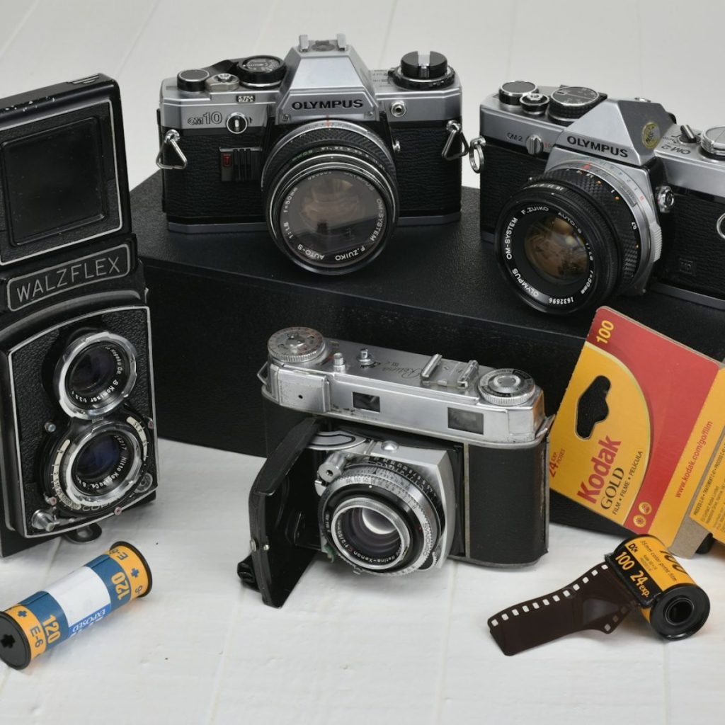 four gray-and-black classic cameras with film rolls