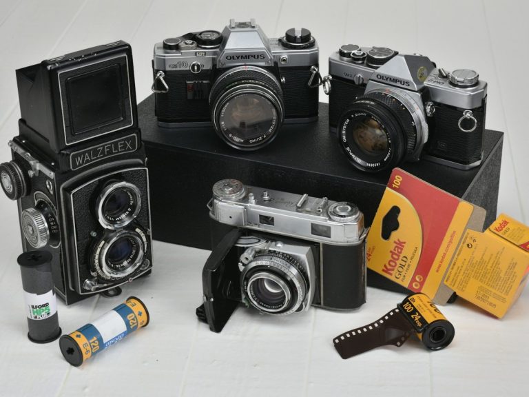 four gray-and-black classic cameras with film rolls